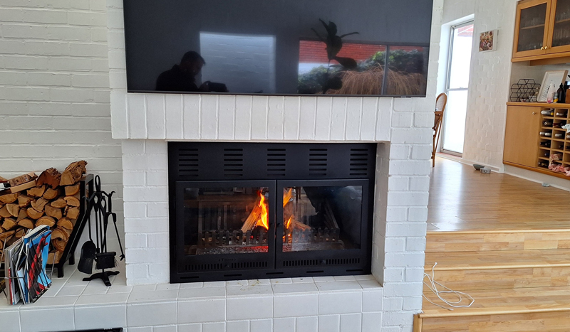 Custom frame with glass door added to an existing steel fireplace turning it into a slow-burner.